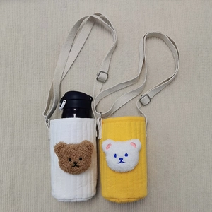 Detailed view of quilted cotton water bottle carriers with cute bear embroidery and straps