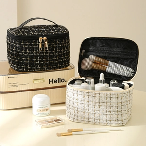 Detail showing open white and closed black tweed makeup bags with brushes and compartments