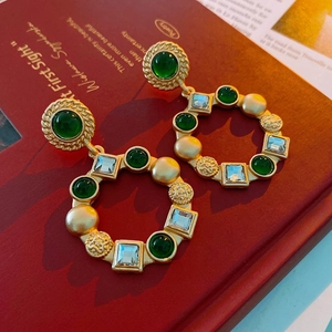 Vintage court style gold hoop earrings with emerald gemstones and crystals on red books