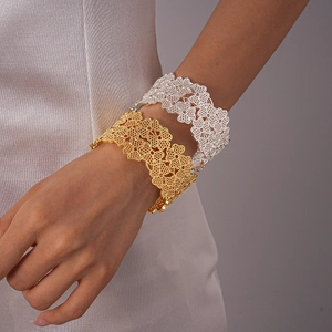 Détails de bracelets ajourés en métal doré et argenté avec motifs de fleurs au poignet