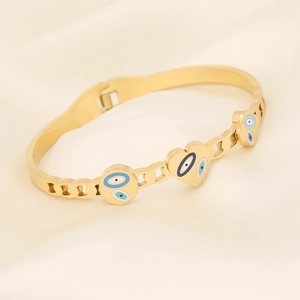 Golden stainless steel snake bracelet with evil eye charms on beige silk background