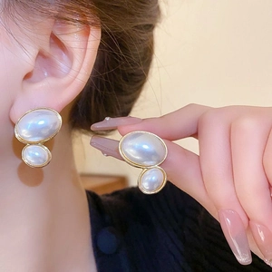 Close-up of elegant double-layered oval pearl earrings with gold metallic borders