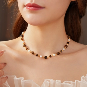 Close-up of vintage tiger eye and pearl necklace worn on neck with gold bead accents