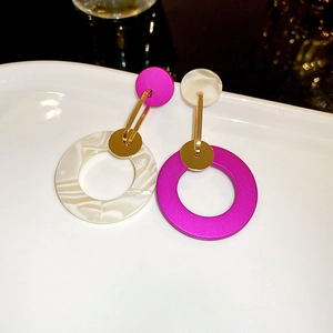 Macro detail of geometric drop earrings with magenta and marble textured resin circles