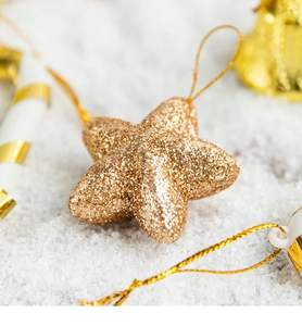 Close-up of golden star Christmas ornament with glitter finish on snow background