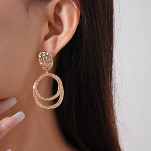 Gros plan de boucles d'oreilles dorées géométriques avec texture martelée