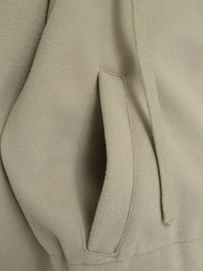 Detailed macro view of soft beige fabric featuring a side pocket and woven drawstring tie