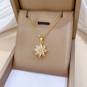 Close-up of golden eight-petal flower pendant with sparkling zircons on jewelry box