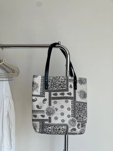 Close-up of vintage paisley canvas tote bag hanging on a minimalist steel rack