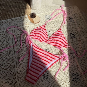 Dettaglio bikini a righe rosa e rosse con trama in maglia su pizzo decorativo