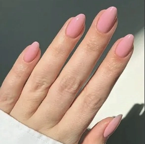 Primer plano de uñas postizas brillantes rosa claro en forma de almendra para mujer