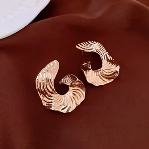 Exaggerated golden geometric fan-shaped earrings on a luxurious silk background
