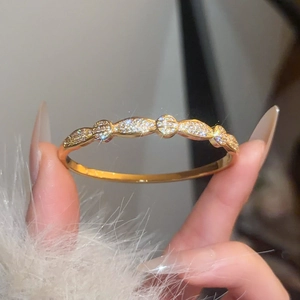 Macro detail of gold plated zircon bangle featuring intricate hollow leaf and circle design