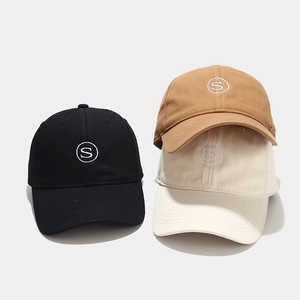 Detail of three cotton baseball caps with S embroidery in black, khaki, and beige colors