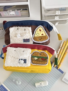 Detail eines Federmäppchens aus Segeltuch mit Burger-Stickerei und Plüschelementen