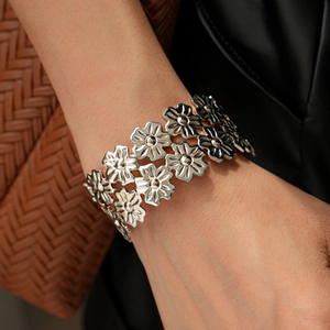 Detailed view of silver flower open bangle featuring hollow daisy patterns on wrist
