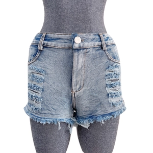 Dettaglio degli shorts in denim azzurro con strappi pesanti e orli sfrangiati a mano