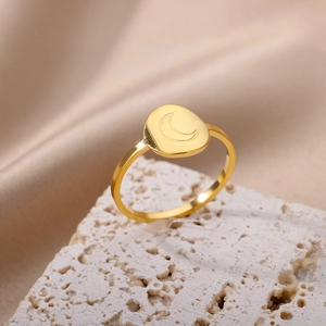 Macro shot of 18K gold stainless steel ring with crescent moon engraving on porous stone