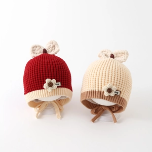 Detail of knit baby hats with decorative bows, yarn flowers, and protective ear flaps