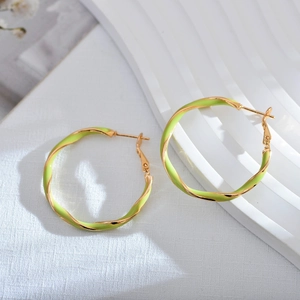 Elegant gold and light green enamel twisted hoop earrings on a white marble background
