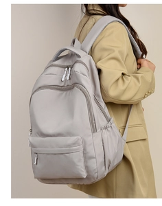 Minimalist light grey nylon backpack with multi-pocket design shown on model's back