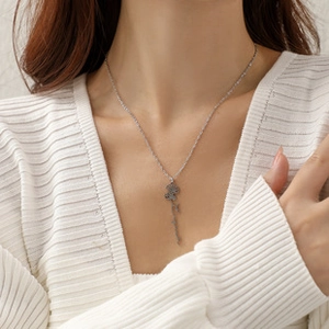 Detail shot of a silver rose flower pendant necklace with elegant letter script worn by model
