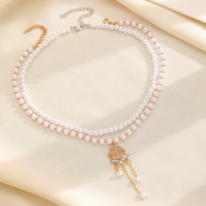 Detail of double-layer pearl necklace with a gold flower pendant and crystal fringe