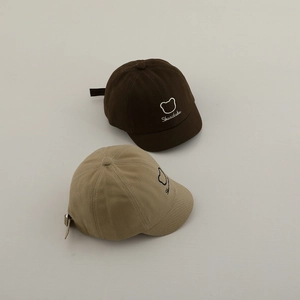 Détail de la broderie ours et de la texture coton sur casquettes bébé marron et kaki