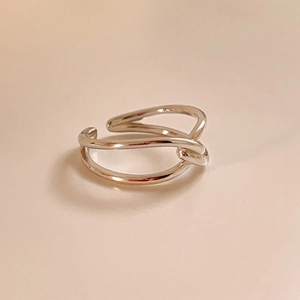 Macro view of minimalist silver knotted open ring with polished metallic finish and texture