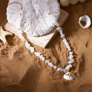 Detail of white crushed stone choker with gold starfish and shell on a beach