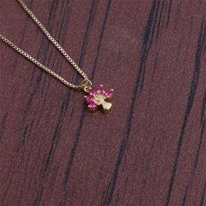 Detail of gold tree of life necklace with red crystals on dark wooden background