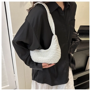 Detail of white popcorn textured shoulder bag showing unique pleated surface on model