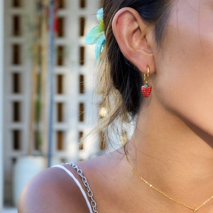 Close-up of red strawberry drop earring with green leaves on 18K gold plated steel