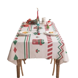 Christmas tablecloth with red and green geometric festive patterns and fringe on a wooden table