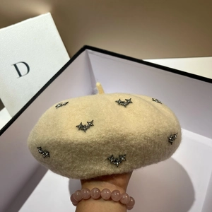 Detailed texture of beige wool beret with black rhinestone star embellishments
