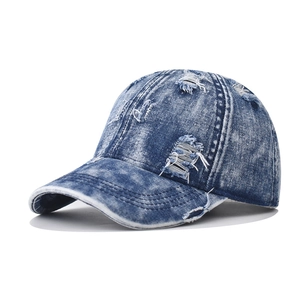 Detailed close-up showing the distressed texture and holes on the blue denim baseball cap