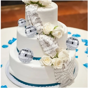 Close-up of silver mirror disco ball cake toppers on a white tiered wedding cake