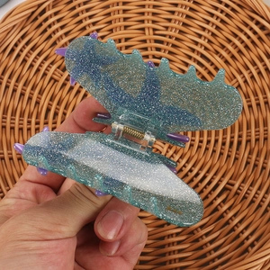 Macro shot of whale tail hair claw clip with blue-green gradient and glitter accents