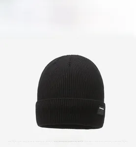 Close-up of black ribbed knit beanie with side logo patch and premium texture detail