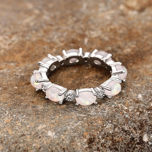 Gros plan d'une bague éternité en argent avec opales roses et pierres sur roche