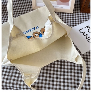 Detaillierte Draufsicht auf beige Canvas-Tasche mit Bärenprint und Plüsch-Anhänger