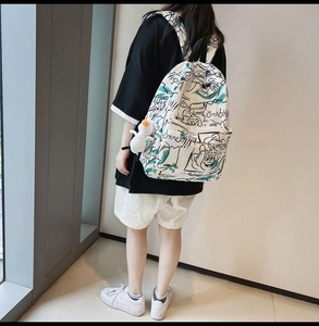 Detail of white graffiti backpack with green accents and a cute plush duck pendant