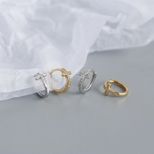 Detailed view of silver and gold cross hoop earrings with sparkling crystal pavé stones