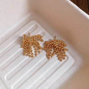 Macro shot of gold plated firework tassel earrings with delicate beaded chains