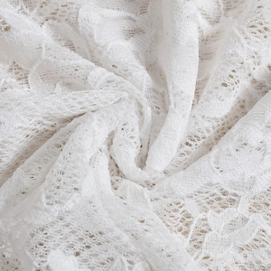Macro detail of white floral lace fabric showing intricate mesh texture and sheer pattern