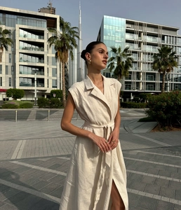 Detail of beige sleeveless shirt dress featuring a tailored lapel and belted waist design