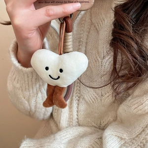 Close-up of fluffy heart-shaped charm with a smile on a cream knitted background