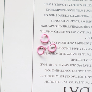 Detailed close-up of three pink painted metal jump rings for DIY jewelry making