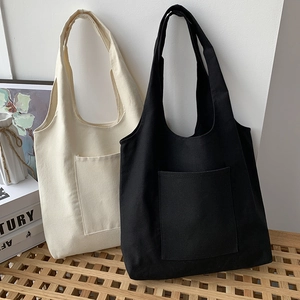 Close-up of cream and black canvas tote bags with front pockets and minimalist design