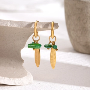 18k gold-plated leaf earrings with green natural stone charms on a stone display